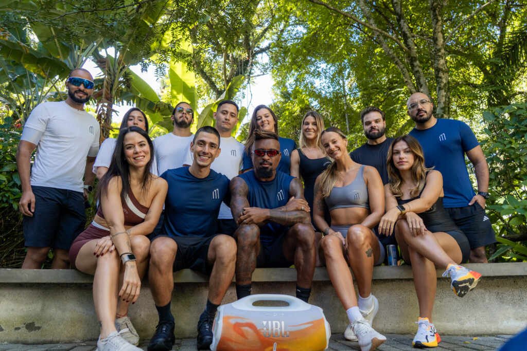 Zé Roberto e grupo posam após treino no Parque Ibirapuera durante o Programa Movimento 11; participantes usam roupas do evento e há uma caixa de som JBL no primeiro plano.